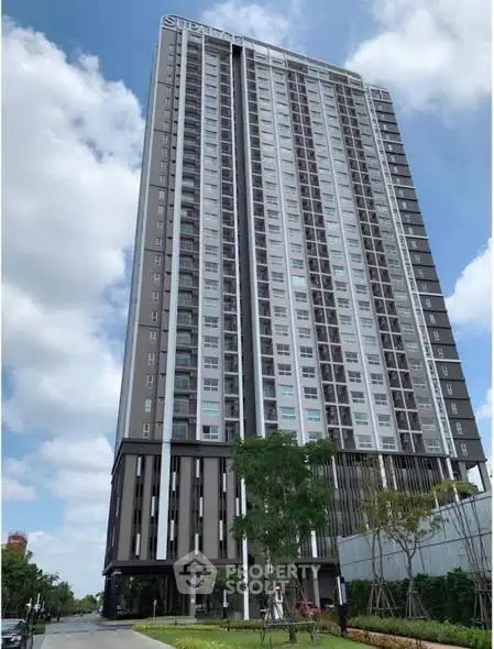 Modern high-rise residential building with sleek design and lush surroundings.