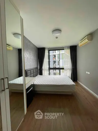 Modern bedroom with large window and stylish decor in a high-rise apartment.
