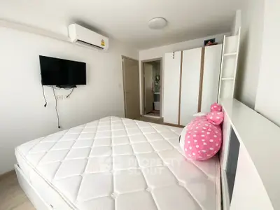 Spacious bedroom with modern amenities and stylish decor, featuring a comfortable mattress and wall-mounted TV.
