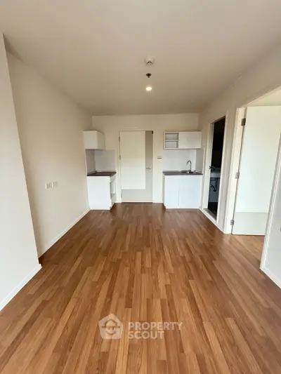 Spacious open-plan living area with wooden flooring and modern kitchenette.