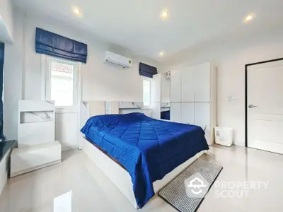 Spacious bedroom with modern decor and blue accents, featuring ample natural light and sleek furnishings.