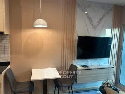 Modern living room with stylish decor, wall-mounted TV, and cozy dining area.