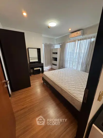 Spacious bedroom with large windows and modern furnishings, featuring a comfortable bed and ample natural light.