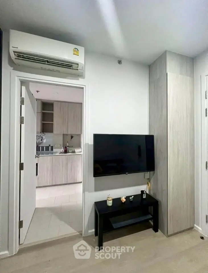 Modern living room with wall-mounted TV and view into stylish kitchen
