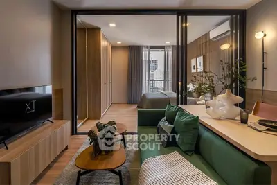 Modern living room with green sofa, stylish decor, and view into cozy bedroom with cityscape.