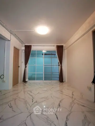 Spacious living room with elegant marble flooring and large windows for natural light.