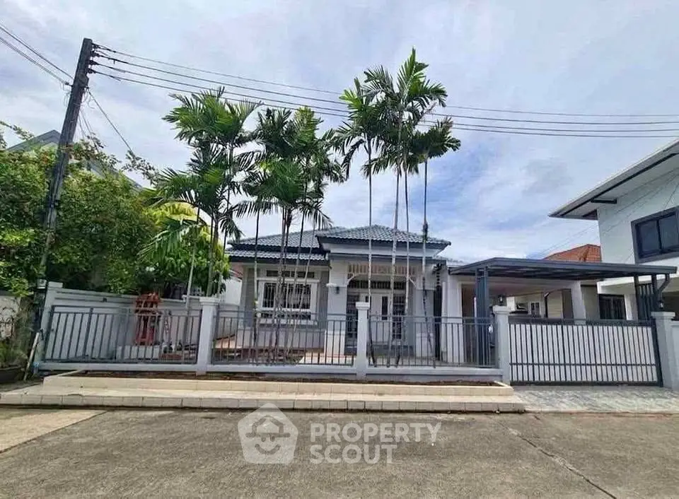 Charming single-story home with lush palm trees and modern fence in a serene neighborhood.