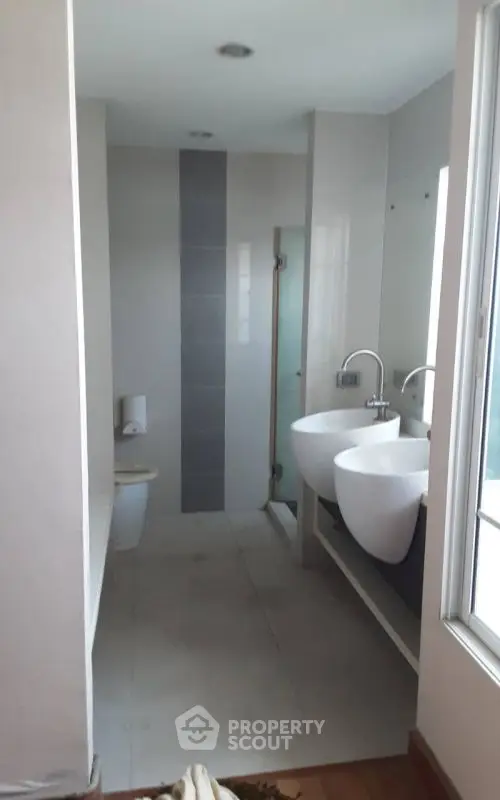 Modern bathroom with dual sinks and glass shower enclosure.