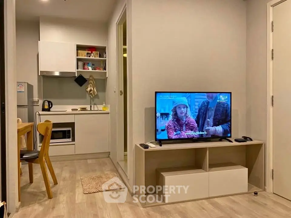 Cozy living room with modern kitchen, TV, and dining area in compact apartment.