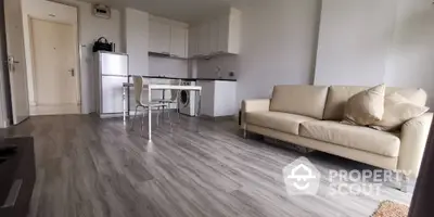 Modern open-plan living room with kitchen, featuring sleek flooring and neutral decor.