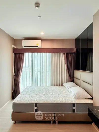Spacious bedroom with large window and modern decor in a stylish apartment.