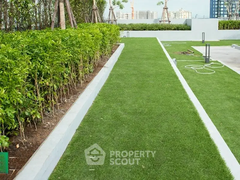 Lush green garden area with manicured lawns and modern landscaping in a residential complex.