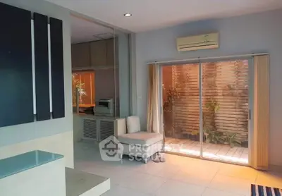 Modern living room with sliding glass doors to a private patio, featuring sleek decor and air conditioning.