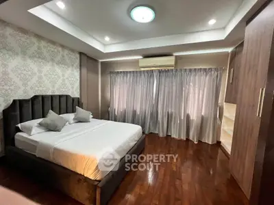 Luxurious bedroom with elegant decor and hardwood floors, featuring a cozy bed and ample natural light.