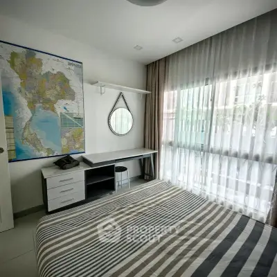 Cozy bedroom with striped bedding, study desk, and large window with sheer curtains.
