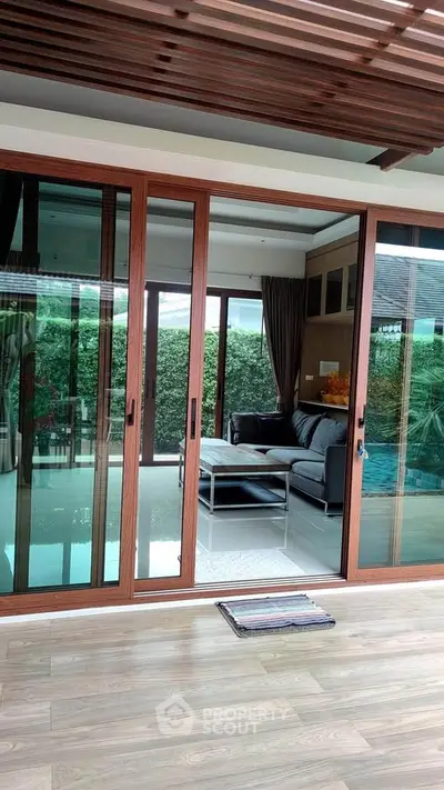 Luxurious living room with sliding glass doors opening to a lush garden view, featuring elegant wooden flooring.