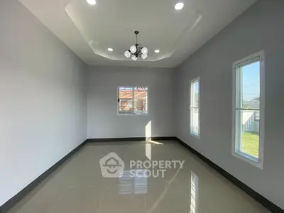 Spacious empty room with modern chandelier and large windows