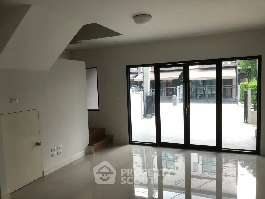 Spacious modern living room with large glass doors opening to a patio, perfect for natural light.