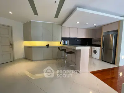 Modern kitchen with sleek cabinetry, breakfast bar, and stainless steel appliances in a stylish apartment.