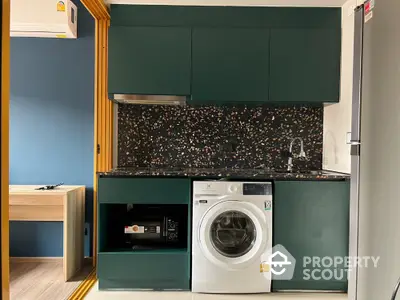 Modern kitchen with green cabinets, washing machine, and stylish backsplash