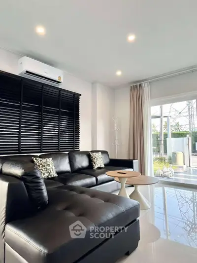 Modern living room with black leather sofa and large window view