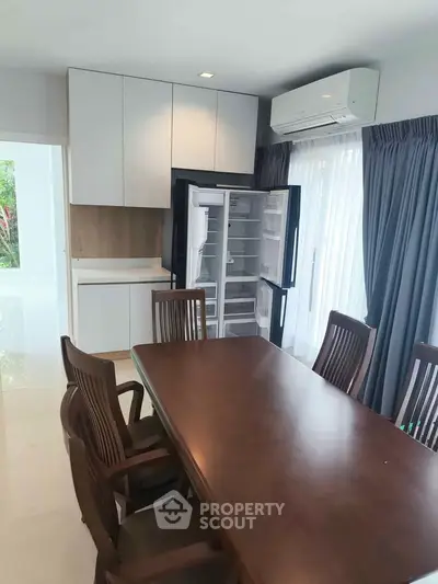 Modern dining area with open fridge and elegant wooden table set.