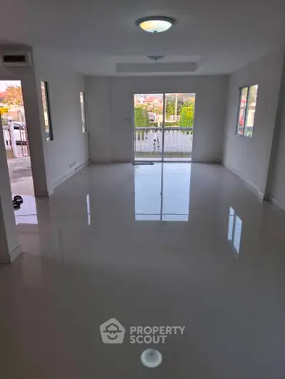 Spacious unfurnished living room with glossy white flooring and large windows.