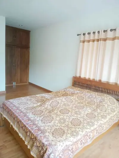 Cozy bedroom with wooden furniture and elegant curtains in a serene setting.