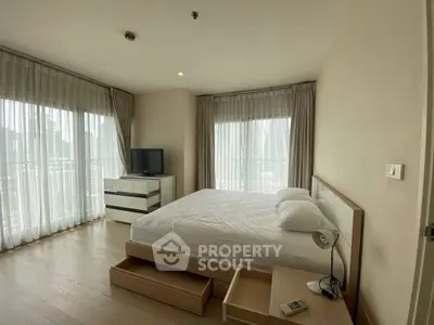 Spacious bedroom with modern furnishings and large windows offering city views.