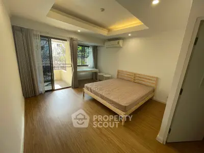 Spacious bedroom with balcony access and modern wooden flooring