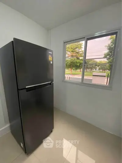 Modern kitchen with sleek black refrigerator and large window view.