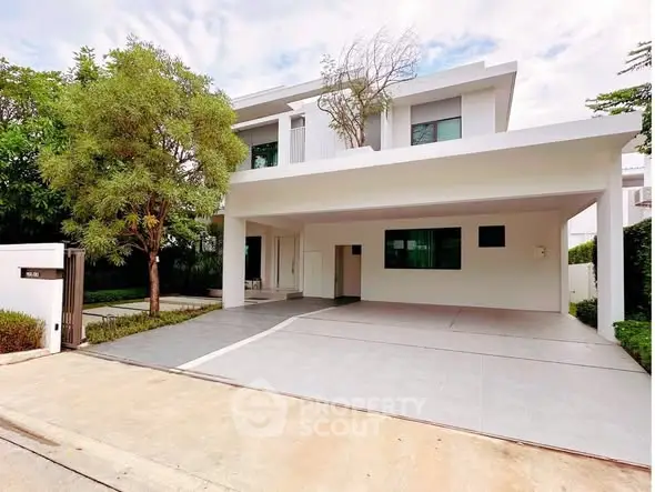 Modern two-story house with spacious driveway and lush greenery.