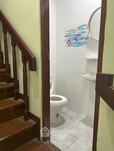 Cozy bathroom with nautical-themed decor next to wooden staircase