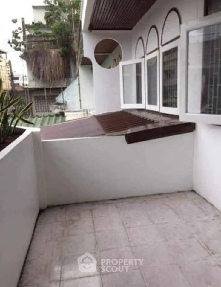 Charming balcony with open windows and urban view, perfect for relaxation.