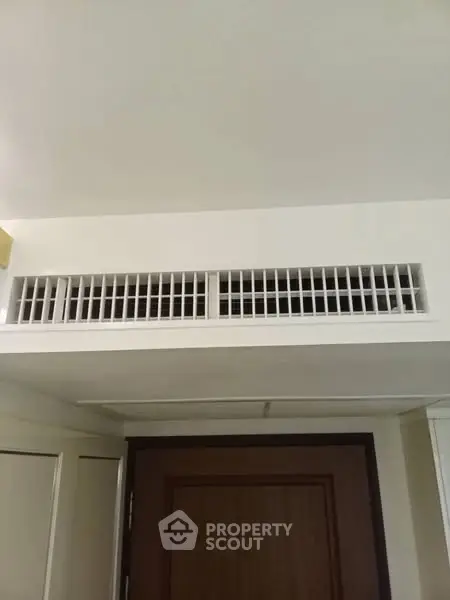 Modern interior with air vent above wooden door, showcasing efficient ventilation system.