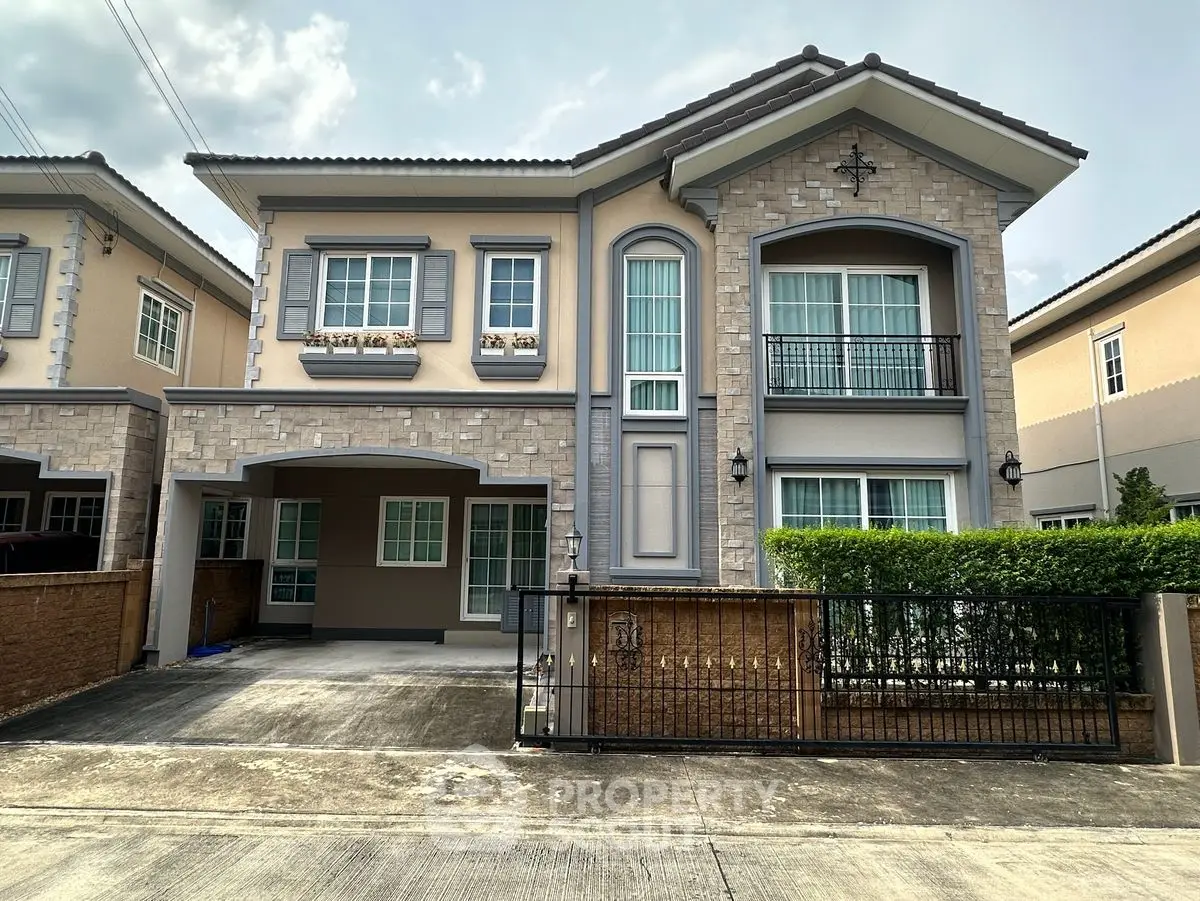 Elegant two-story house with stone facade and manicured hedges in a suburban neighborhood.