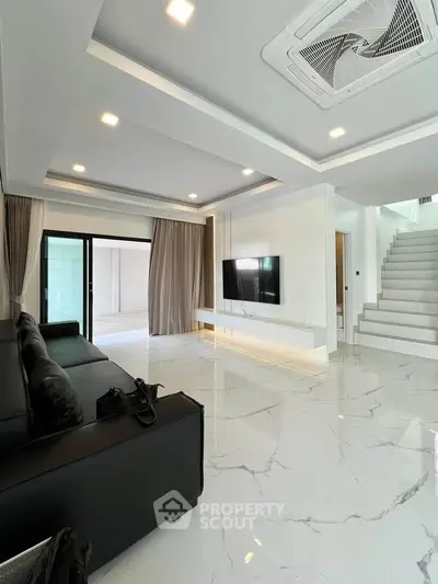 Luxurious modern living room with sleek marble flooring and stylish black leather sofa.