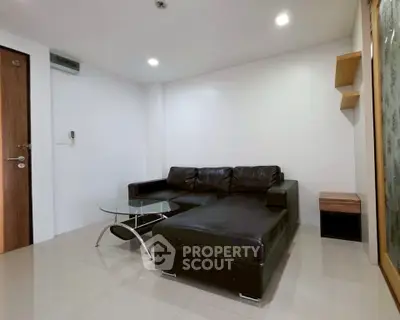 Modern living room with sleek black leather sofa and glass coffee table