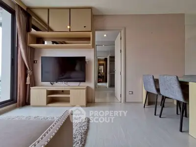 Modern living room with large TV and dining area in stylish apartment.