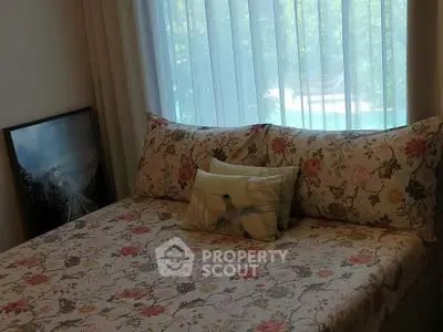 Cozy bedroom with floral bedding and scenic artwork by window with garden view.