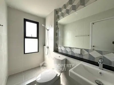 Modern bathroom with geometric tile accents and natural light