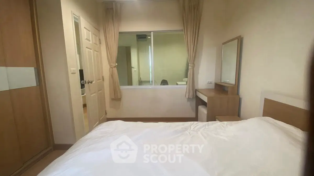 Cozy bedroom with wooden furniture and large window for natural light.