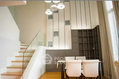 Modern dining area with stylish staircase and elegant lighting in a contemporary home.