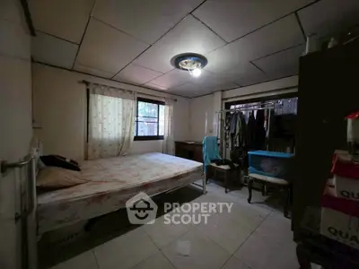Cozy bedroom with natural light, featuring a bed, wardrobe, and tiled flooring, ideal for comfortable living.