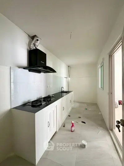 Modern kitchen with sleek black countertop and gas stove in a bright, minimalist design.