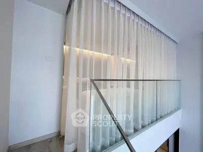 Modern duplex interior with elegant glass railing and sheer curtains