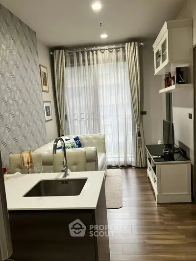 Modern living room with open kitchen, stylish decor, and natural light.