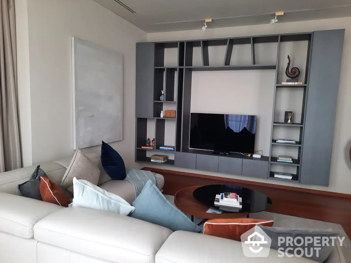 Spacious living room with modern entertainment wall unit, plush sectional sofa, and tasteful decor, ideal for relaxation and hosting.