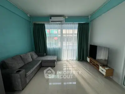 Modern living room with teal walls, large window, and cozy gray sectional sofa.