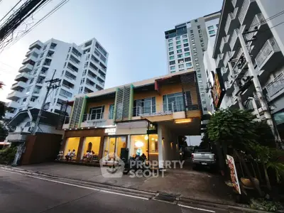 Modern urban building exterior with street view and parked vehicles, showcasing contemporary architecture.